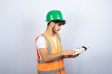 Yeşil şapkalı genç mühendis beyaz arka planda notlar okuyor. Yüksek kalite fotoğraf