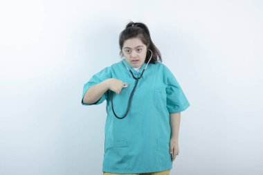 Beyaz duvarda steteskopla duran genç bayan hemşire. Yüksek kalite fotoğraf