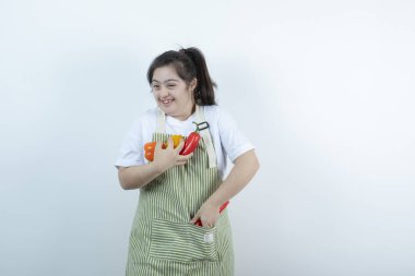 Kareli önlüğün içinde duran ve cebine sebze koyan genç ve güzel bir kız. Yüksek kalite fotoğraf