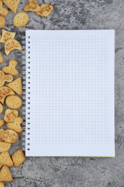 Tuzlu kraker yığını ve mermer arka planda boş defter. Yüksek kalite fotoğraf