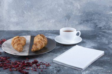 Mermer bir arka planda boş bir defter ile beyaz bir fincan sıcak çay. Yüksek kalite fotoğraf