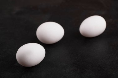 Siyah yüzeyde üç çiğ tavuk yumurtası. Yüksek kalite fotoğraf