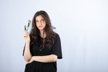 Beyaz arka planda duran, makyajlı genç bir modelin portresi. Yüksek kalite fotoğraf