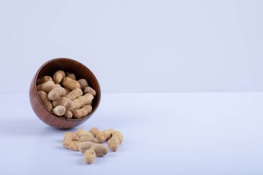 Beyaz arka planda soyulmamış fıstıklarla dolu ahşap bir kase. Yüksek kalite fotoğraf
