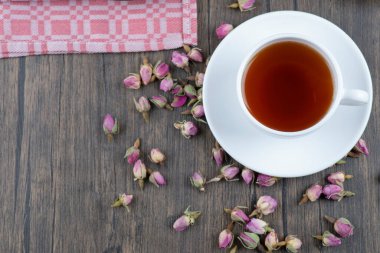 Ahşap bir masaya yerleştirilmiş gül tomurcukları olan bir fincan siyah çay. Yüksek kalite fotoğraf