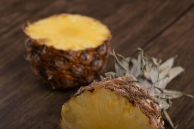 Ahşap zemine yerleştirilmiş lezzetli yarım dilimlenmiş olgun ananas. Yüksek kalite fotoğraf