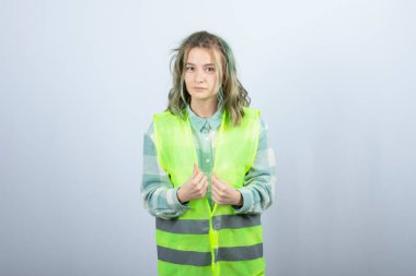 Genç bayan mühendisin beyaz arka planda durup baktığı fotoğraf. Yüksek kalite fotoğraf