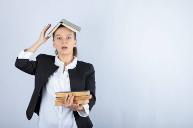 Kafasında bir sürü kitap olan güzel bir öğretmenin resmi. Yüksek kalite fotoğraf