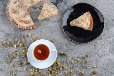 Lezzetli bir parça kek ve beyaz bir fincan sıcak çay ile siyah bir tabak. Yüksek kalite fotoğraf