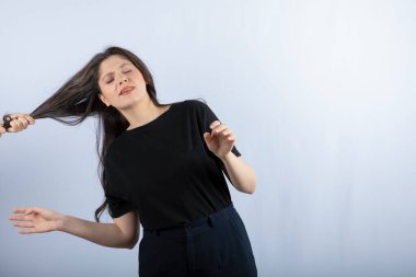 Biri beyaz arka planda genç bir kızın saçını çekiyor. Yüksek kalite fotoğraf