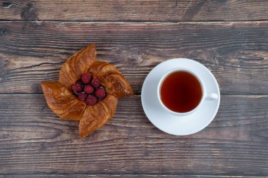 Ahşap masaya bir fincan siyah çay konmuş lezzetli ahududulu börek. Yüksek kalite fotoğraf