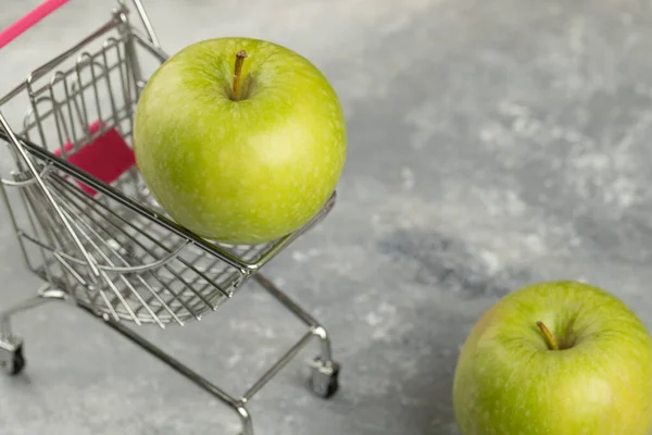 大理石の背景に金属ショッピングカートで緑の新鮮なリンゴ 高品質の写真 — ストック写真
