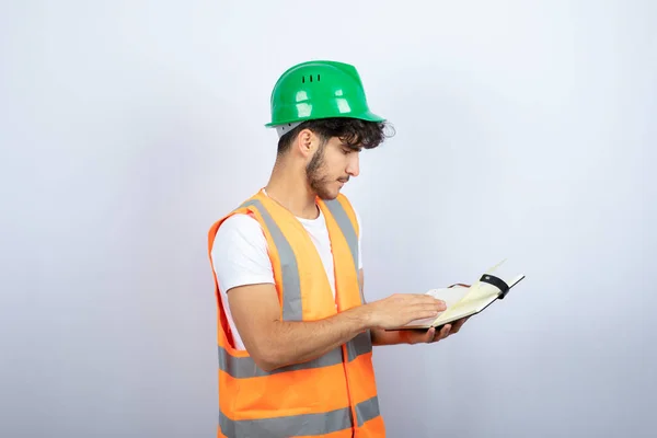 Joven Ingeniero Masculino Hardhat Verde Leyendo Notas Sobre Fondo Blanco — Foto de Stock