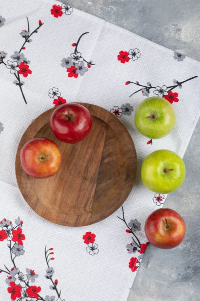 Mermer yüzeyde taze kırmızı ve yeşil elmalardan oluşan ahşap bir tabak. Yüksek kalite fotoğraf
