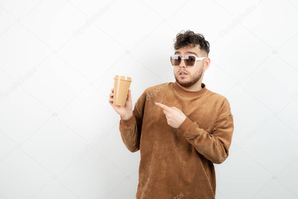 Photo of young man in glasses holding cup of coffee. High quality photo