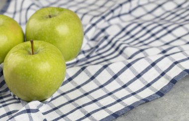 Çizgili masa örtüsüne yerleştirilmiş lezzetli yeşil elmalar. Yüksek kalite fotoğraf