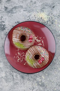 Kırmızı çikolatalı çörekler, mermer yüzeyine çilek ve serpiştirilmiş. Yüksek kalite fotoğraf