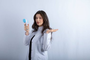 Termometreyi tutan ve beyaz arka planda duran genç bir doktorun görüntüsü. Yüksek kalite fotoğraf