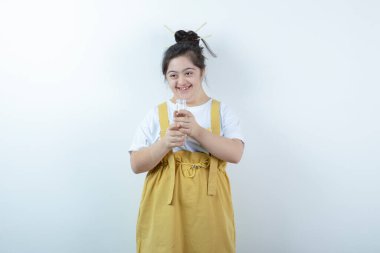 Genç ve güzel kız model ayakta ve beyaz duvara karşı cam şişe tutuyor. Yüksek kalite fotoğraf