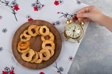 Elma halkalarının olduğu tahta tabağın yanında alarmlı saati tutan kadın. Yüksek kalite fotoğraf