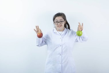 Doktor üniformalı genç bir kız elinde yeşil ve kırmızı elma meyveleri tutuyor. Yüksek kalite fotoğraf