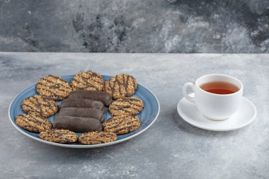 Mavi tabak dolusu çikolatalı kek ve bir fincan sıcak çayla kepekli kurabiye. Yüksek kalite fotoğraf