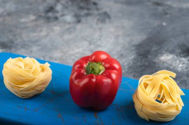 Kırmızı dolma biber ve çiğ tagliatelle makarnası mavi kesim tahtasında. Yüksek kalite fotoğraf
