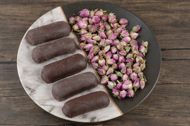 Bir tabak dolusu çikolatalı kremalı rulo süt ve ahşap bir masada kurumuş güller. Yüksek kalite fotoğraf