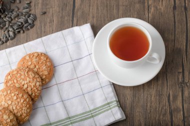 Tahta bir masaya yerleştirilmiş beyaz fincanlı çok tahıllı kurabiyeler. Yüksek kalite fotoğraf
