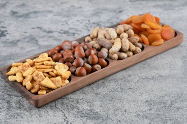 Tahta tabak dolusu fındık, kraker ve mermer yüzeyde kurutulmuş kayısı. Yüksek kalite fotoğraf