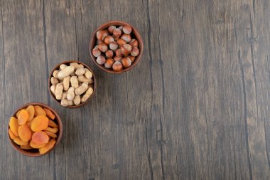 Tahta masada kurutulmuş kayısı meyveleri ve sağlıklı fındıklarla dolu tahta kaseler. Yüksek kalite fotoğraf
