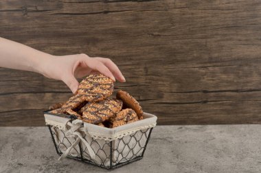 Kadın el mermer yüzeydeki sepetten taze pişmiş kurabiyeler alıyor. Yüksek kalite fotoğraf