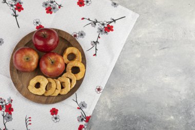 Kurutulmuş elma halkaları ve beyaz masa örtüsünün üzerinde taze kırmızı elmalar. Yüksek kalite fotoğraf