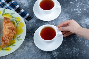 Renkli bir tabak taze kruvasan ve mermer zemine konmuş beyaz çay. Yüksek kalite fotoğraf