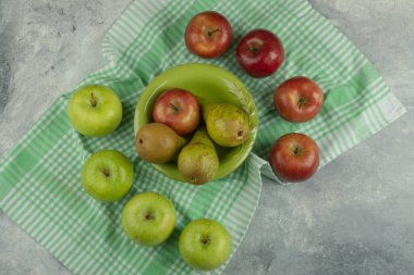 Mermer yüzeyde taze elma ve armut dolu yeşil kase. Yüksek kalite fotoğraf