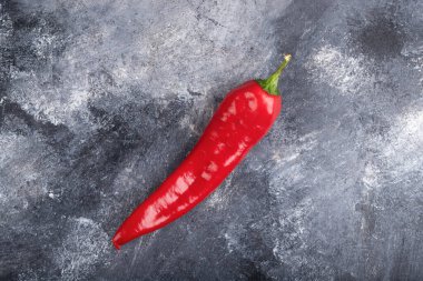 Single organic chili pepper placed on marble surface. High quality photo