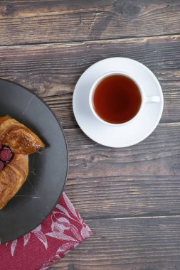 Ahşap bir masada bir tabak lezzetli ahududu pastası ve bir fincan çay. Yüksek kalite fotoğraf