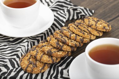 Tahta bir masaya yerleştirilmiş beyaz fincanlı çok tahıllı kurabiyeler. Yüksek kalite fotoğraf