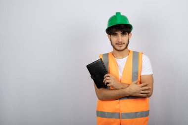 Yeşil şapkalı genç erkek mühendis beyaz arka planda defter tutuyor. Yüksek kalite fotoğraf