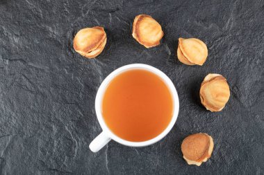 Ceviz şeklinde kurabiyeler ve siyah arka planda bir fincan sıcak çay. Yüksek kalite fotoğraf