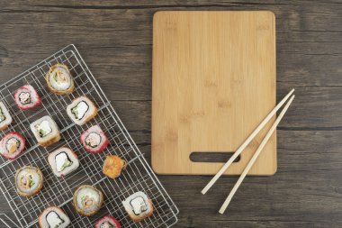 Ahşap zemin üzerinde çubuklar olan çeşitli suşi ruloları. Yüksek kalite fotoğraf