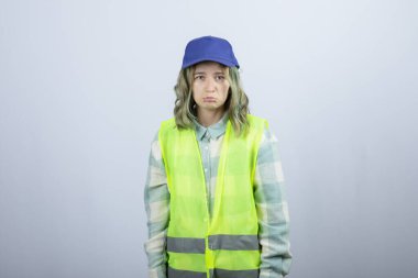 Üniformalı genç bayan mimar, beyaz duvarın arkasında üzgün bir ifadeyle dikiliyor. Yüksek kalite fotoğraf