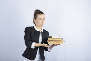 Beyaz arka plan üzerine kitapları tutmaya çalışan genç bir öğrenci görüntüsü. Yüksek kalite fotoğraf