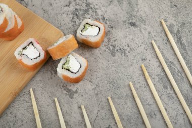Taş zeminde taze somonla süslenmiş lezzetli suşi ruloları. Yüksek kalite fotoğraf