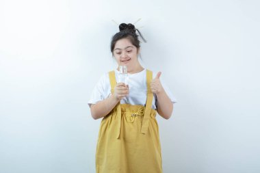 Genç ve güzel kız model ayakta ve beyaz duvara karşı cam şişe tutuyor. Yüksek kalite fotoğraf