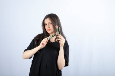 Makyajlı, beyaz arka planda fırçaları olan genç ve güzel bir model. Yüksek kalite fotoğraf