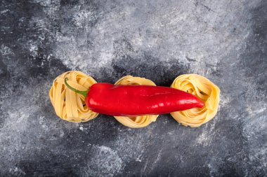 Mermer yüzeyinde kırmızı biberli çiğ makarna yuvaları. Yüksek kalite fotoğraf