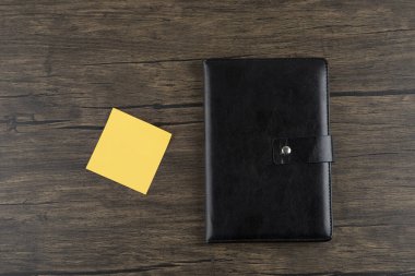 Ahşap arka planda not defteri olan sarı kare çıkartma. Yüksek kalite fotoğraf