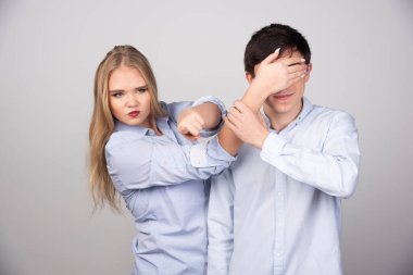 Gri arka planda erkek arkadaşlarının gözlerini kapatan genç bir kadın. Yüksek kalite fotoğraf