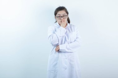 Doktor üniformalı genç bayan ayakta ve sessiz işareti yapıyor. Yüksek kalite fotoğraf